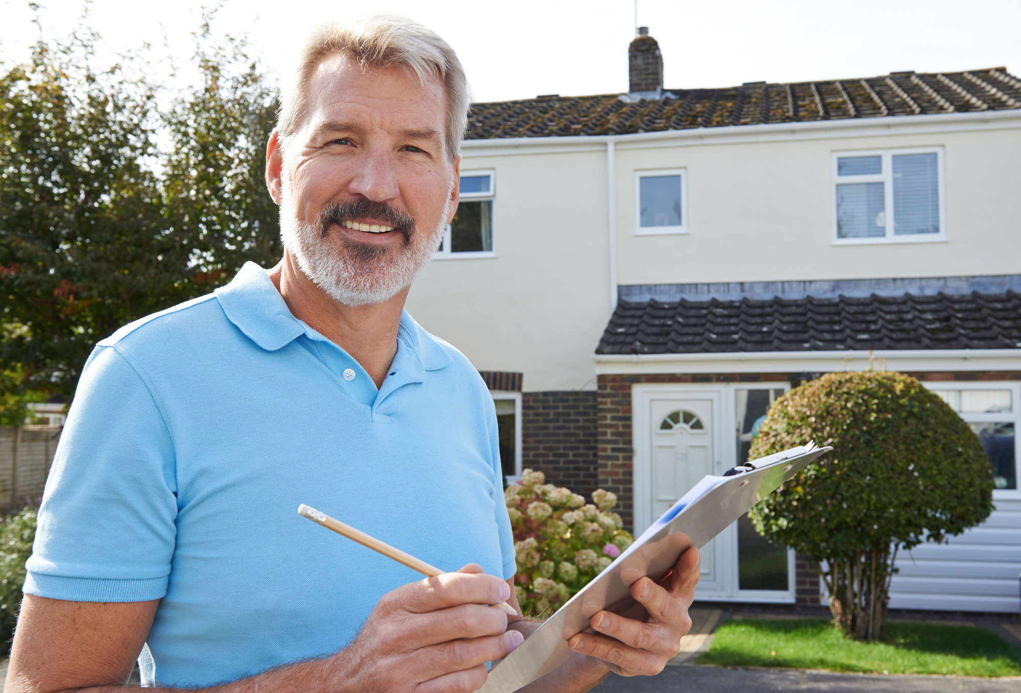 A man smiling while holding a pencil and a list